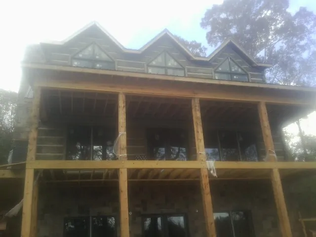 Dormers and porch framing on a large log home under construction — Roof Coating work by our crew in Cornwall On Hudson