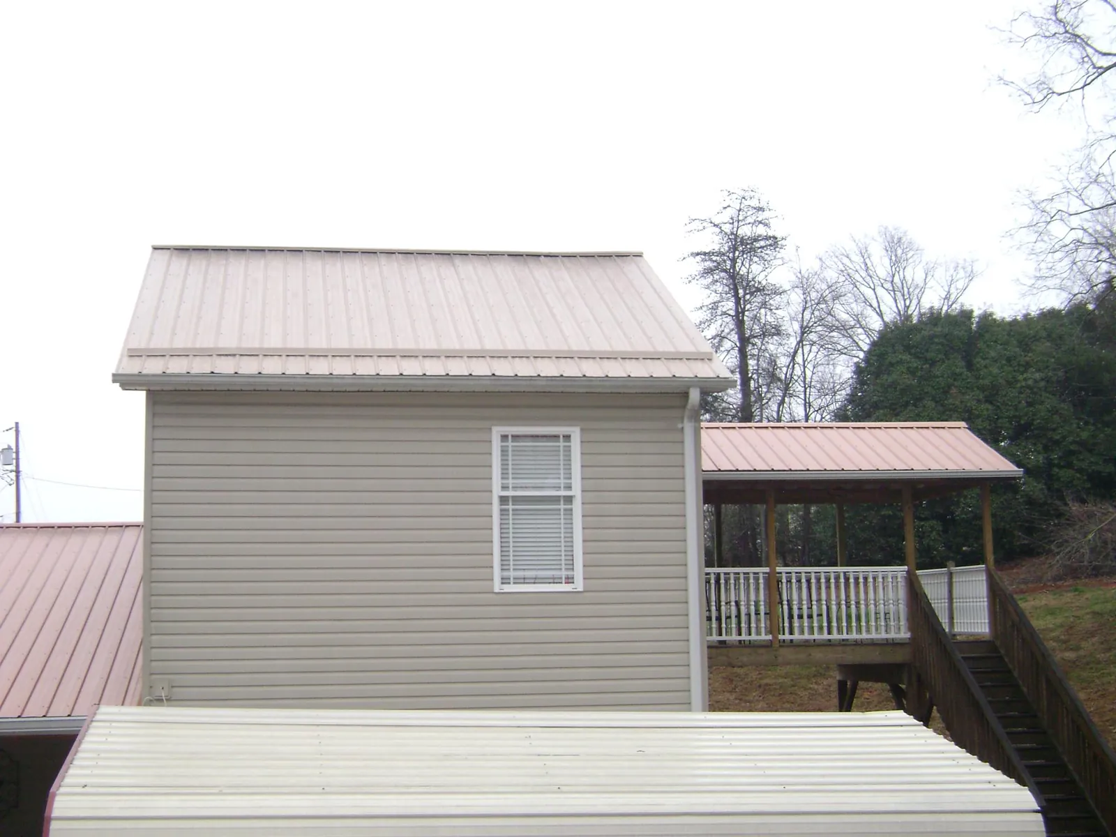 Tan metal roofs on a two story addition and attached porch, from a Roof Replacement job in Cornwall On Hudson