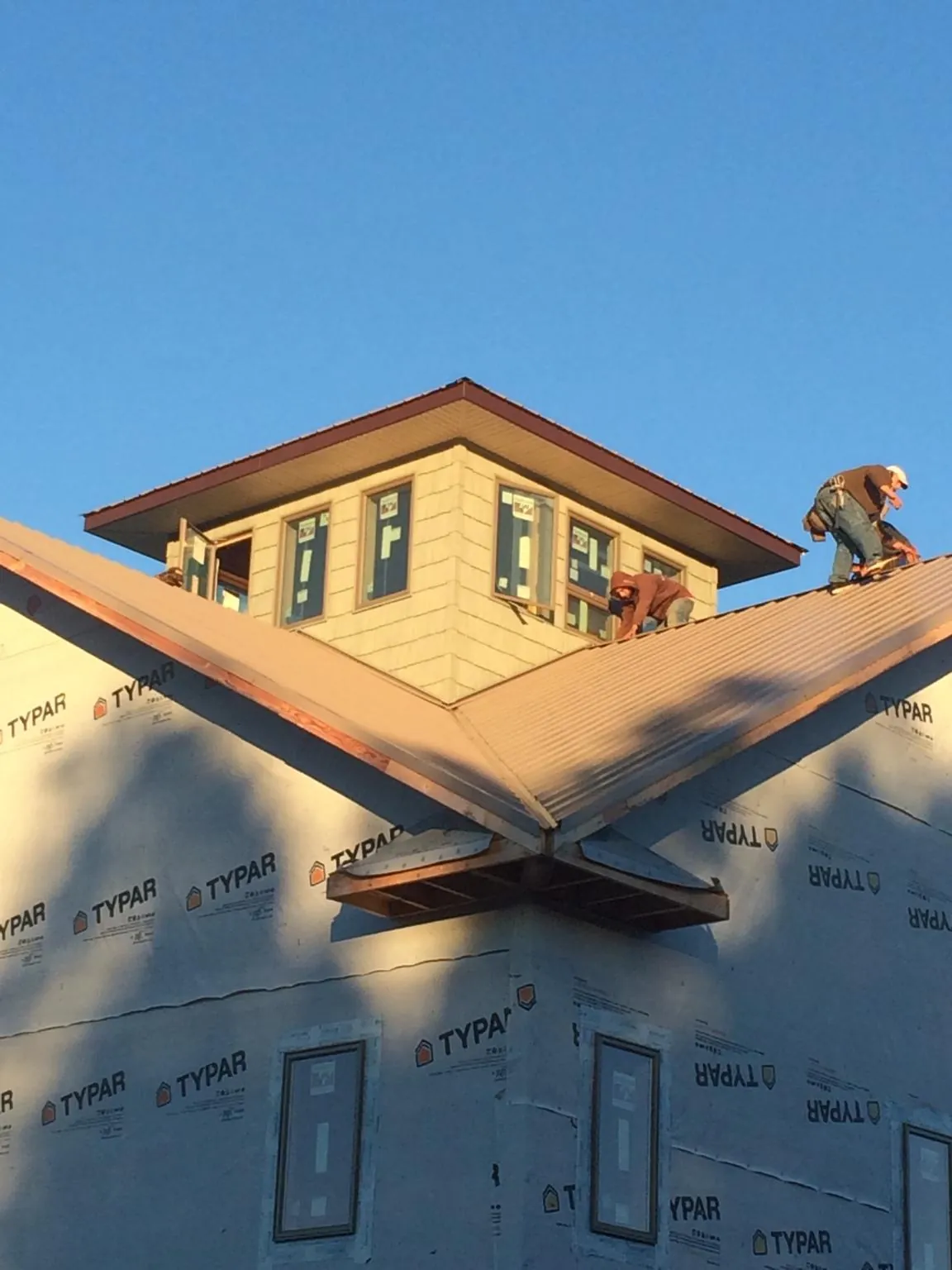 Roofers working around a rooftop cupola on a new metal roof at sunset — Roof Waterproofing in Cornwall On Hudson by Roofing Brothers